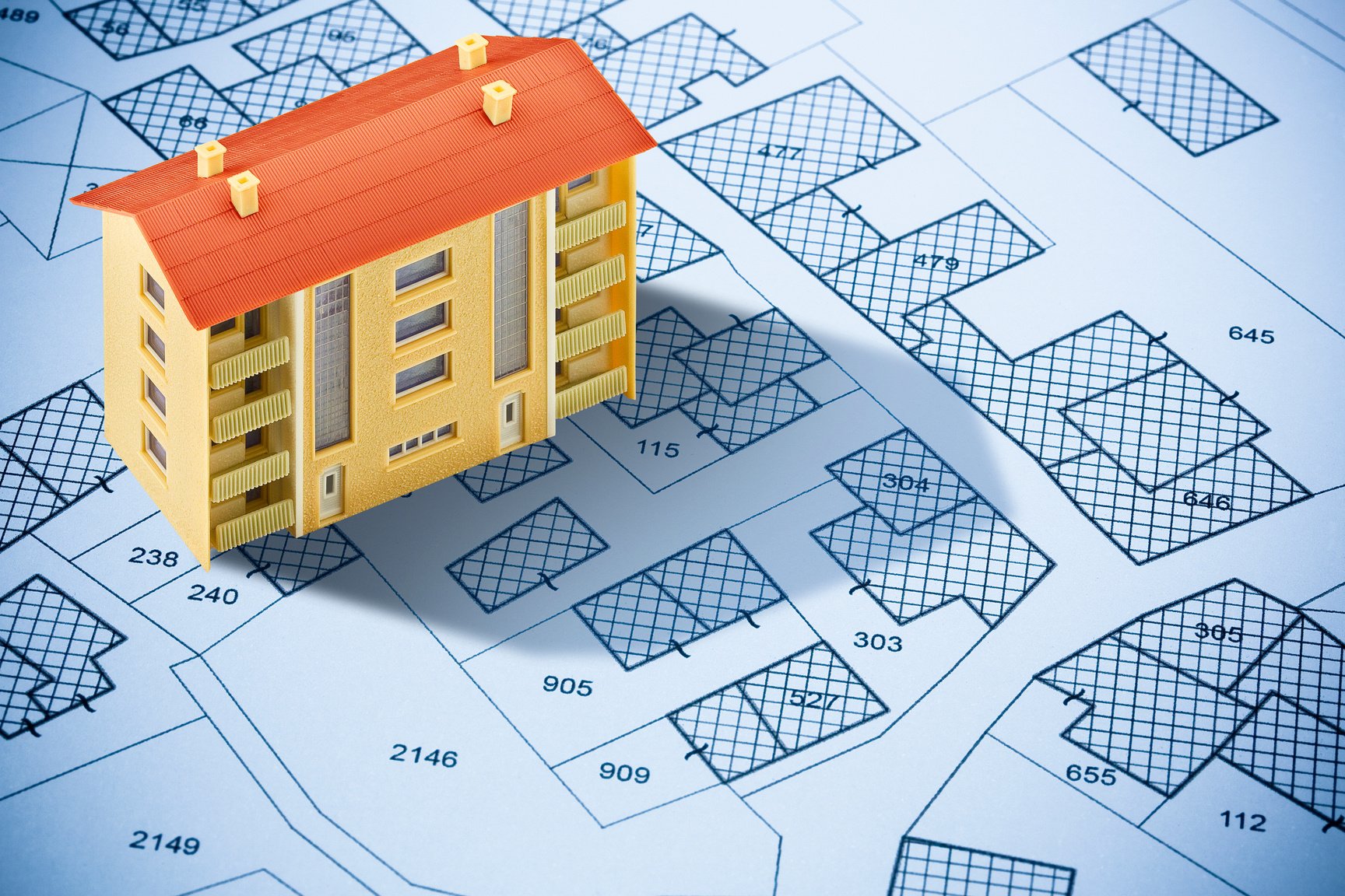 Imaginary cadastral map with cadastral parcels, vacant land plots and condominium residential building model